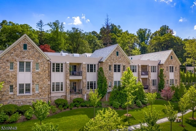 back of property with a lawn and a balcony