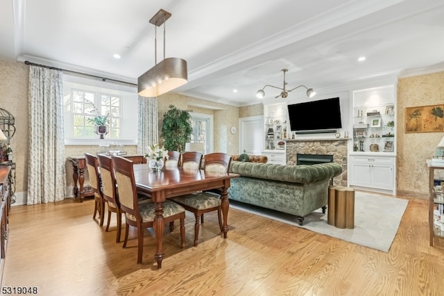 dining room with a fireplace, a chandelier, light wood-type flooring, and built in shelves