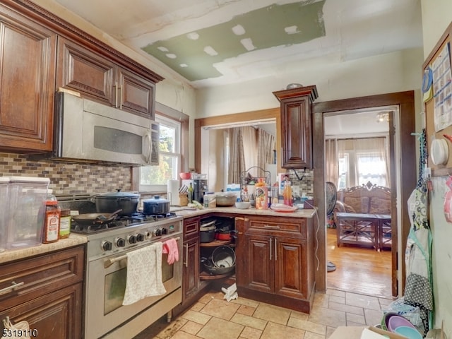 kitchen featuring stainless steel appliances, light wood-type flooring, and tasteful backsplash