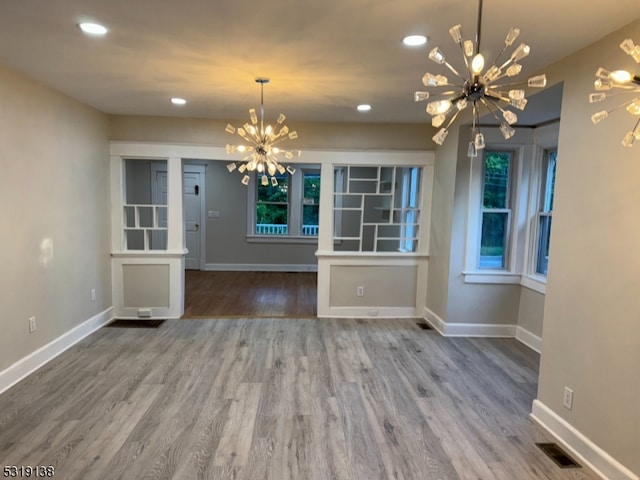 unfurnished dining area featuring an inviting chandelier and hardwood / wood-style floors