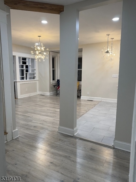 interior space with beamed ceiling, a notable chandelier, and light hardwood / wood-style floors