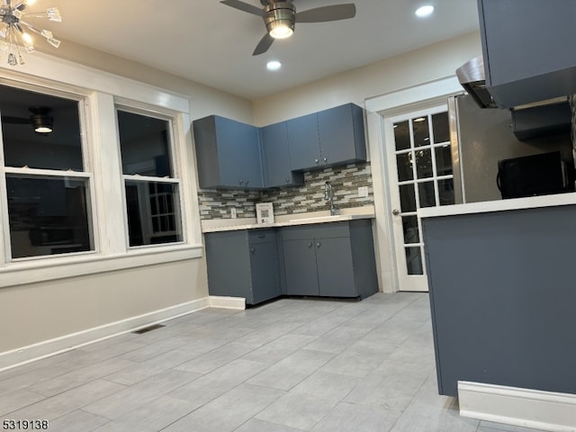 kitchen with ceiling fan, sink, backsplash, and blue cabinets