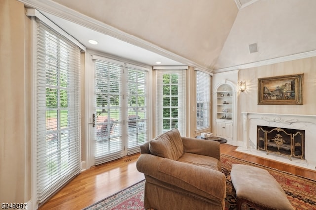 living room with lofted ceiling, a high end fireplace, ornamental molding, and light wood-type flooring