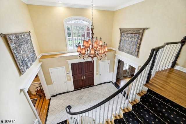 entrance foyer with ornamental molding, a chandelier, and light hardwood / wood-style floors