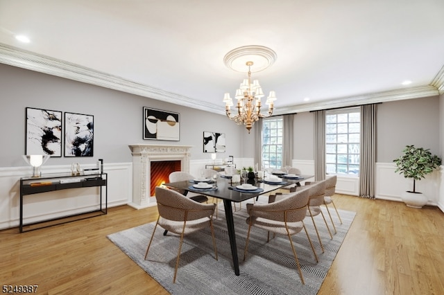 dining space with crown molding, light hardwood / wood-style flooring, and a chandelier