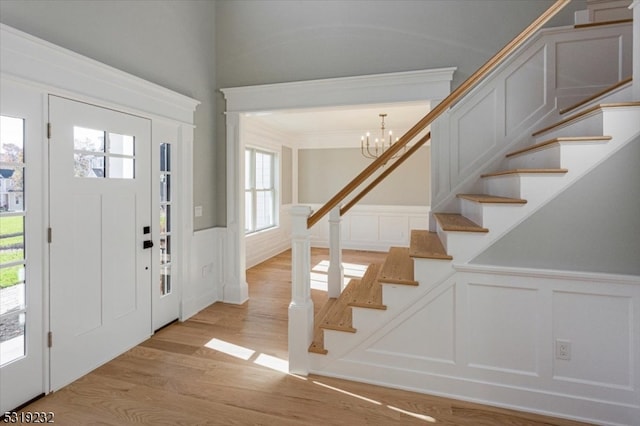 foyer entrance with ornamental molding, a chandelier, and light hardwood / wood-style floors