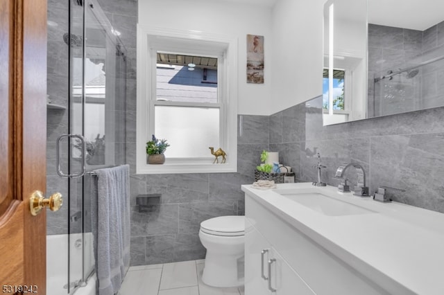 bathroom featuring tile walls, toilet, vanity, an enclosed shower, and tile patterned floors