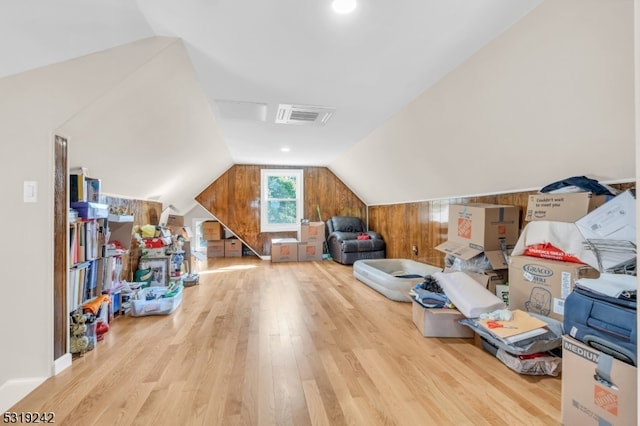 bonus room featuring wood walls, lofted ceiling, and light hardwood / wood-style flooring