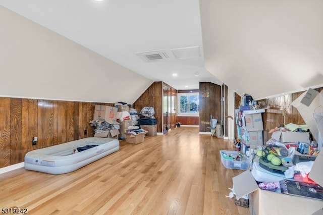 bonus room featuring vaulted ceiling, wood-type flooring, and wood walls