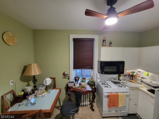 kitchen with white cabinets, white gas stove, and ceiling fan