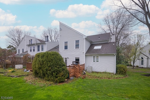 rear view of property with a deck and a lawn