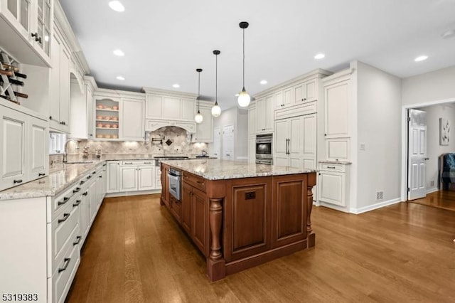 kitchen featuring decorative backsplash, dark wood-type flooring, glass insert cabinets, white cabinets, and a kitchen island