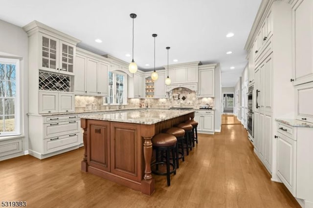 kitchen with glass insert cabinets, tasteful backsplash, a kitchen island, and wood finished floors