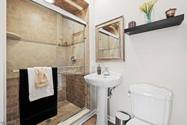 full bathroom featuring a stall shower, a sink, and toilet