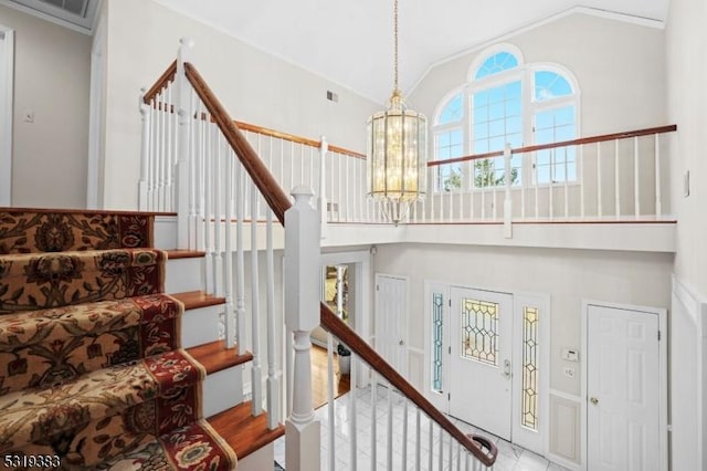 stairway featuring high vaulted ceiling, a chandelier, and visible vents