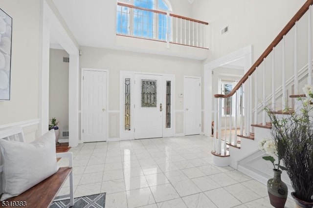 entryway with a wealth of natural light, stairway, a high ceiling, and visible vents