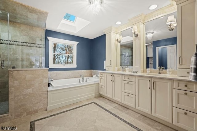 full bathroom featuring double vanity, a skylight, a stall shower, a garden tub, and a sink