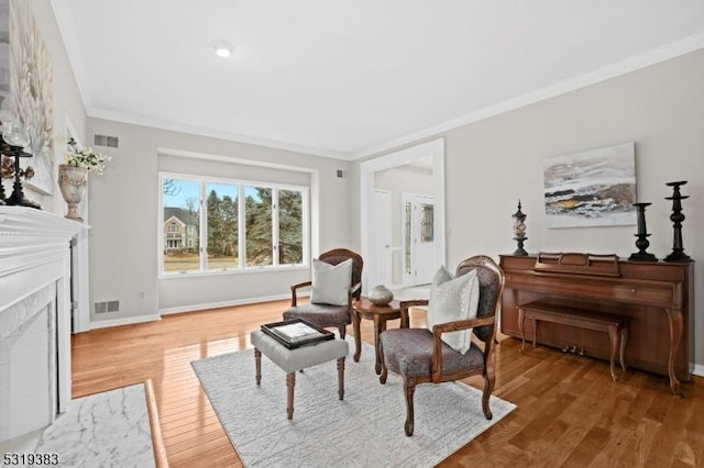 living area featuring light wood finished floors, a high end fireplace, visible vents, and crown molding