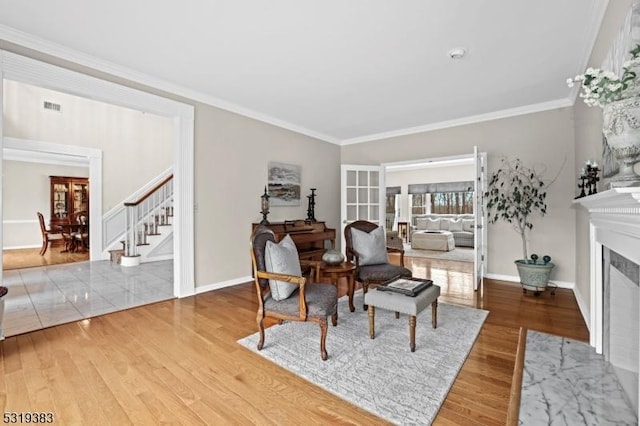 sitting room featuring wood finished floors, a fireplace with flush hearth, visible vents, stairway, and crown molding