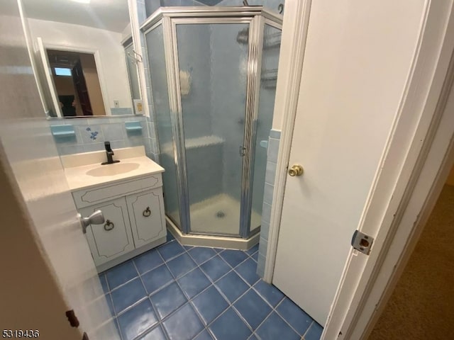 bathroom featuring vanity, a shower with shower door, backsplash, and tile patterned flooring