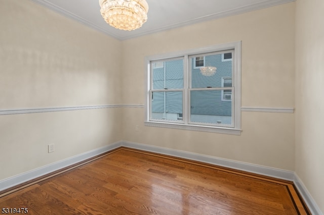 spare room with ornamental molding, hardwood / wood-style floors, and a chandelier