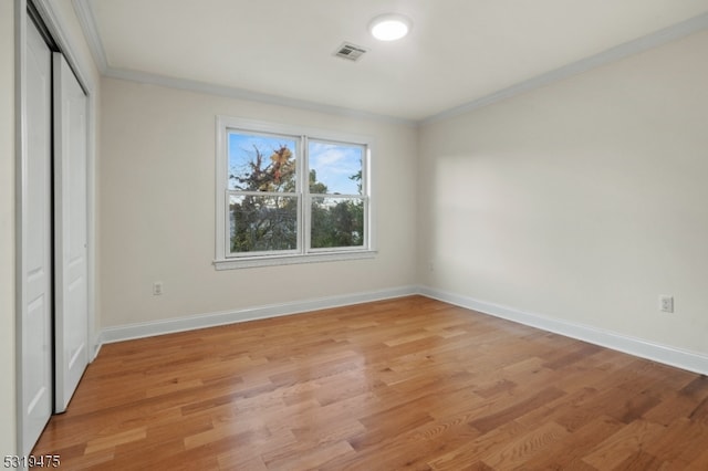 unfurnished bedroom featuring a closet, crown molding, and light hardwood / wood-style floors