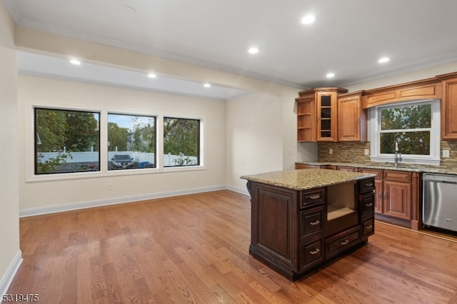 kitchen featuring light stone countertops, wood-type flooring, stainless steel dishwasher, and decorative backsplash