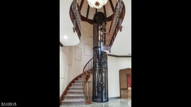 stairway featuring ornamental molding and a high ceiling