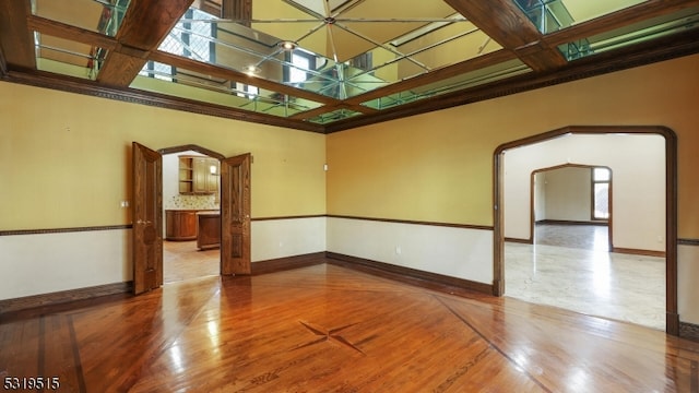 empty room featuring coffered ceiling, hardwood / wood-style flooring, and beamed ceiling