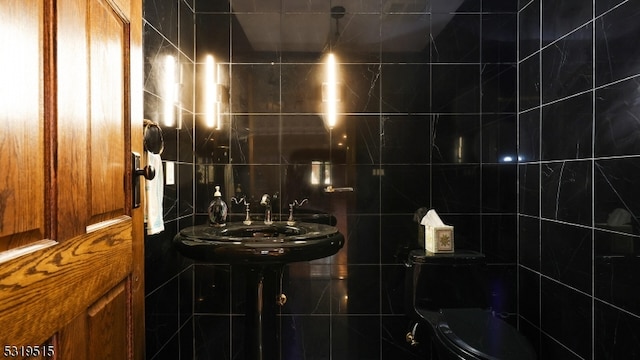 bathroom featuring toilet and tile walls