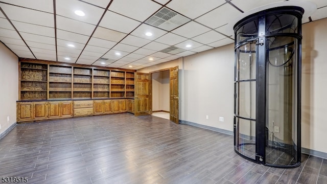 unfurnished living room with dark wood-type flooring and a drop ceiling