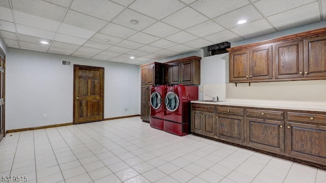 laundry room with cabinets, light tile patterned flooring, sink, and washing machine and dryer