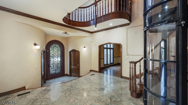 foyer with crown molding and a towering ceiling