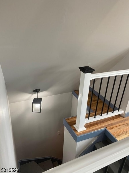 stairway with lofted ceiling and hardwood / wood-style floors