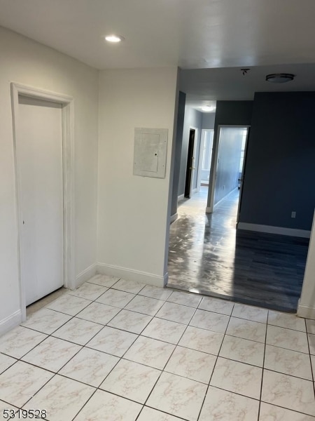 spare room featuring electric panel and light wood-type flooring