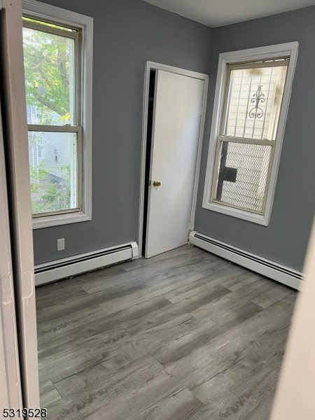 unfurnished room with a baseboard heating unit and a healthy amount of sunlight