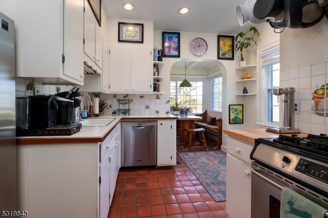 kitchen featuring dark tile patterned flooring, sink, white cabinets, appliances with stainless steel finishes, and tasteful backsplash