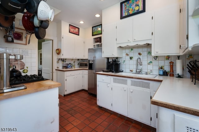 kitchen with backsplash, appliances with stainless steel finishes, sink, and white cabinets