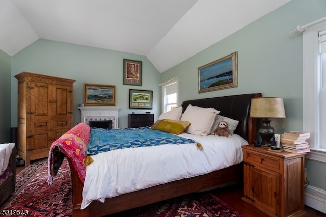 bedroom featuring lofted ceiling and a brick fireplace