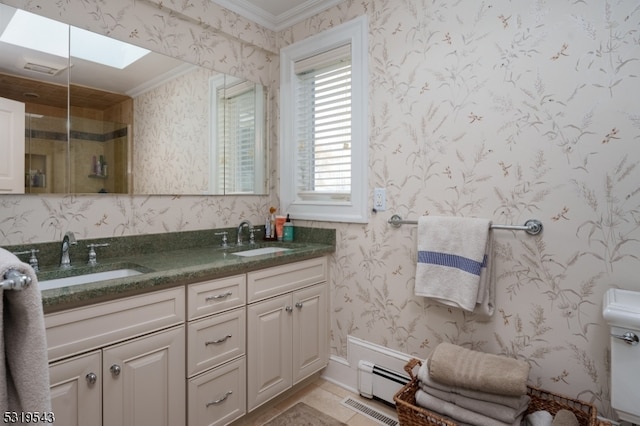 bathroom featuring toilet, a skylight, vanity, crown molding, and baseboard heating