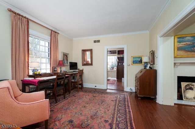 office space featuring dark wood-type flooring, crown molding, and a brick fireplace