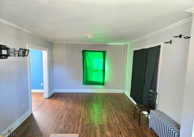 empty room with dark hardwood / wood-style flooring, ornamental molding, and radiator