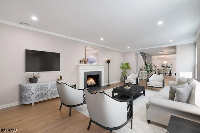 living area featuring visible vents, a warm lit fireplace, baseboards, recessed lighting, and ornamental molding