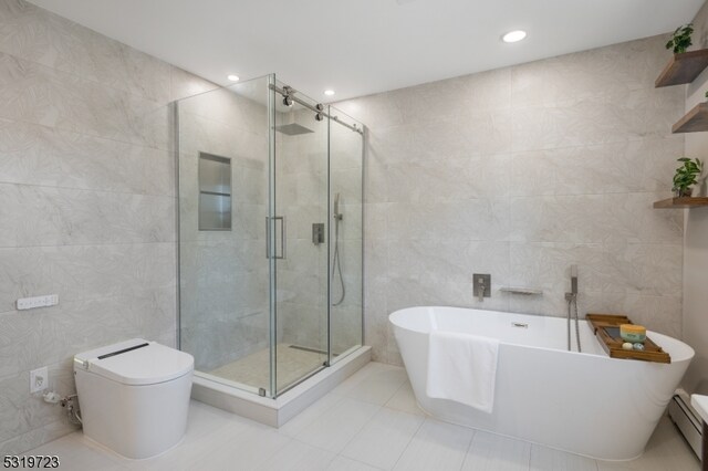 bathroom with a baseboard radiator, shower with separate bathtub, tile patterned floors, and tile walls