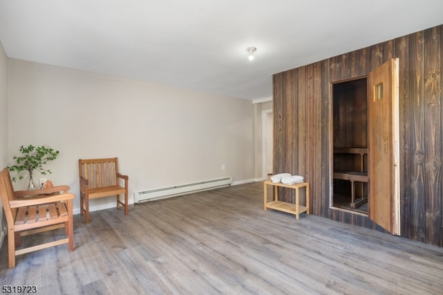 sitting room with light hardwood / wood-style flooring, wooden walls, and a baseboard radiator