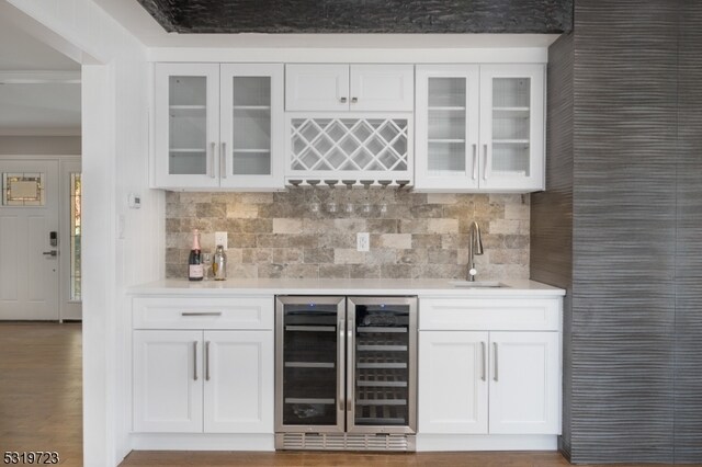 bar with white cabinetry, wine cooler, hardwood / wood-style flooring, and sink