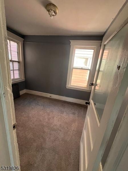 spare room with radiator heating unit and dark carpet