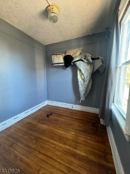 unfurnished room with dark wood-type flooring, a textured ceiling, and a wealth of natural light