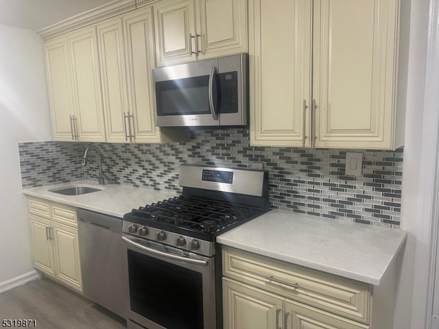 kitchen with backsplash, stainless steel appliances, cream cabinets, and sink