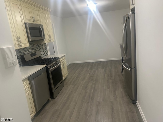 kitchen with backsplash, stainless steel appliances, dark hardwood / wood-style flooring, and cream cabinetry